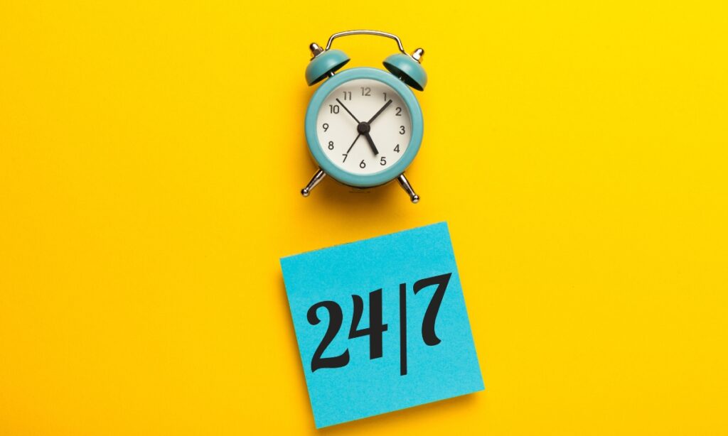 a small teal clock and a sticky note pad with "24/7" written on it