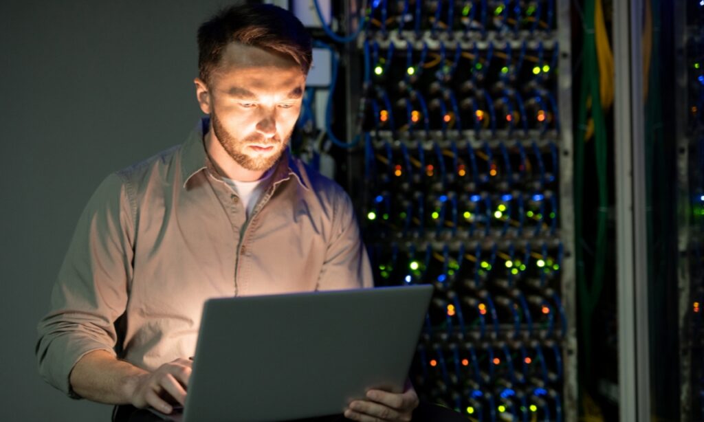 man holding laptop in front of server