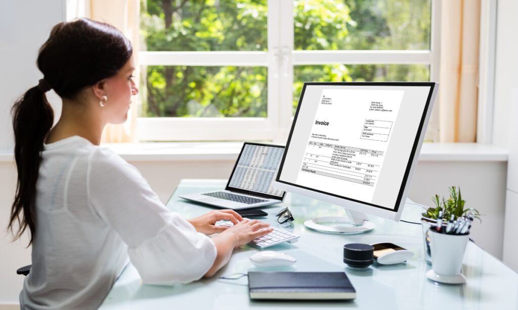 woman sitting at a computer looking at an invoice