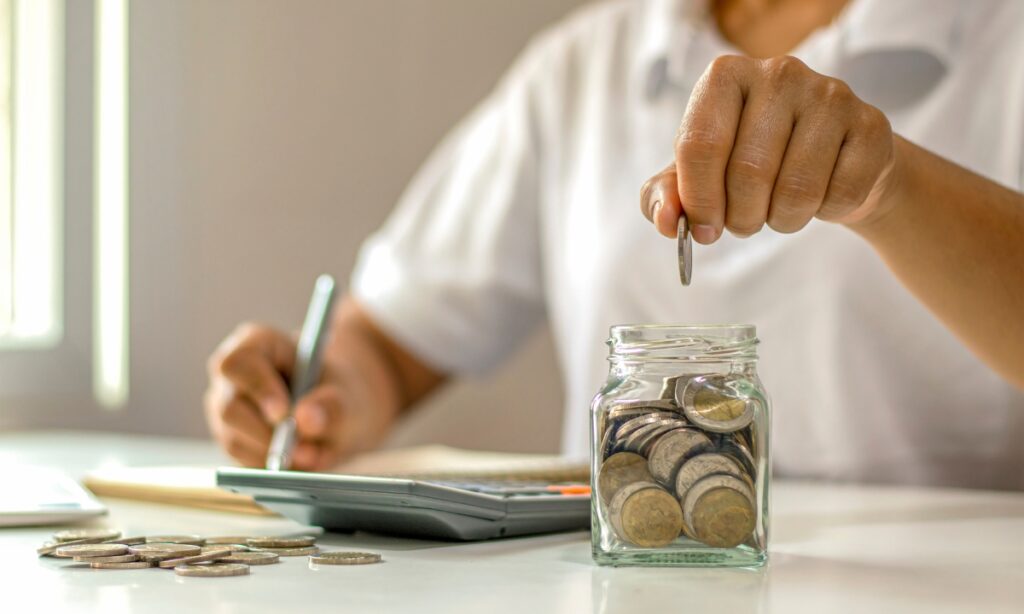 a man doing math and placing money into a jar, used to represent the money someone can save by using IT outsourcing