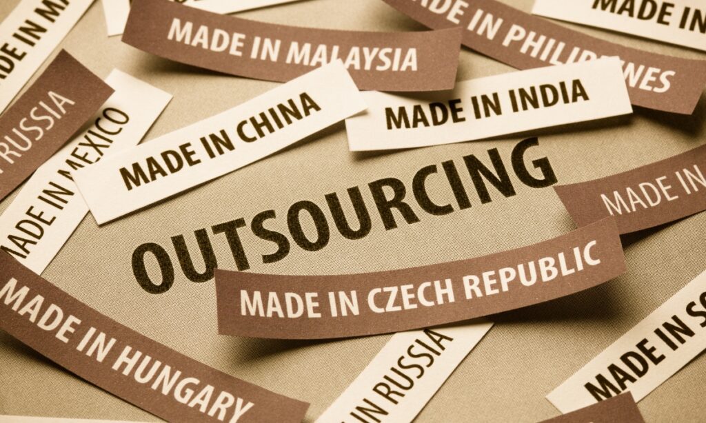 a burlap surface that says "outsourcing" with a number of "made in" slips around it, such as, "made in China," or "made in Czech Republic"