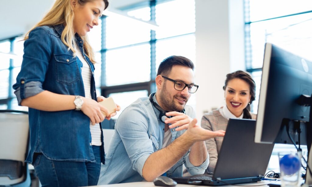 one male and two females look at a computer screen