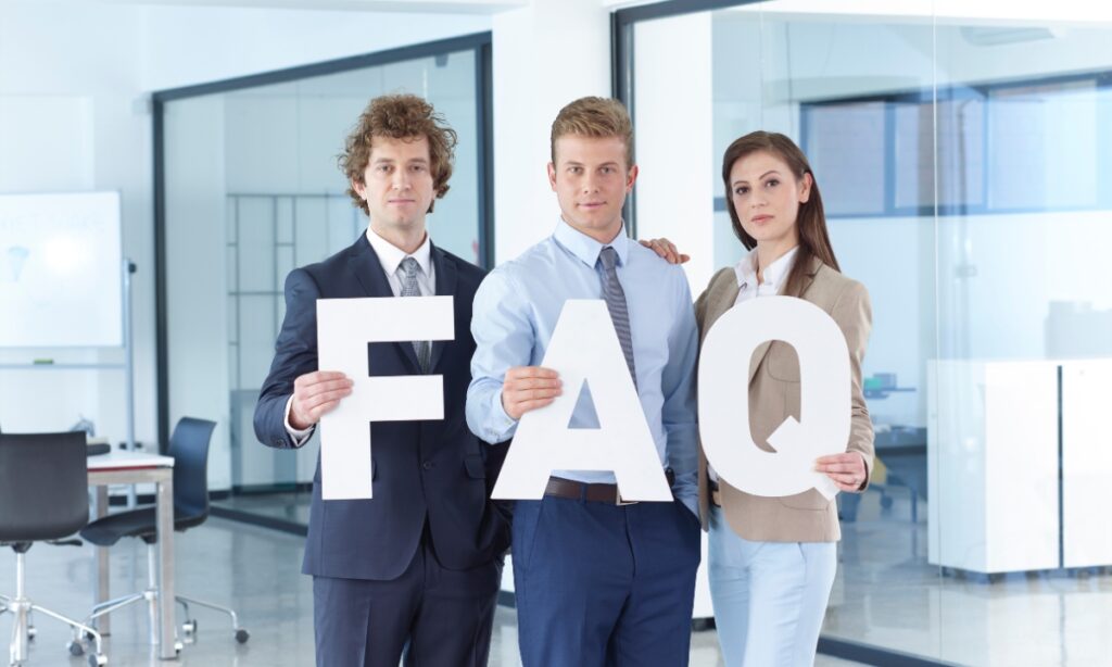 three people in business casual attire in an office holding the letters "f," "a," and "q"