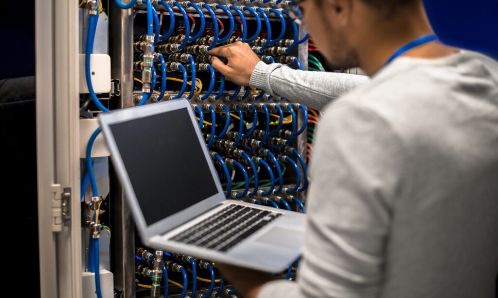 a man holding a laptop and working with a server machine