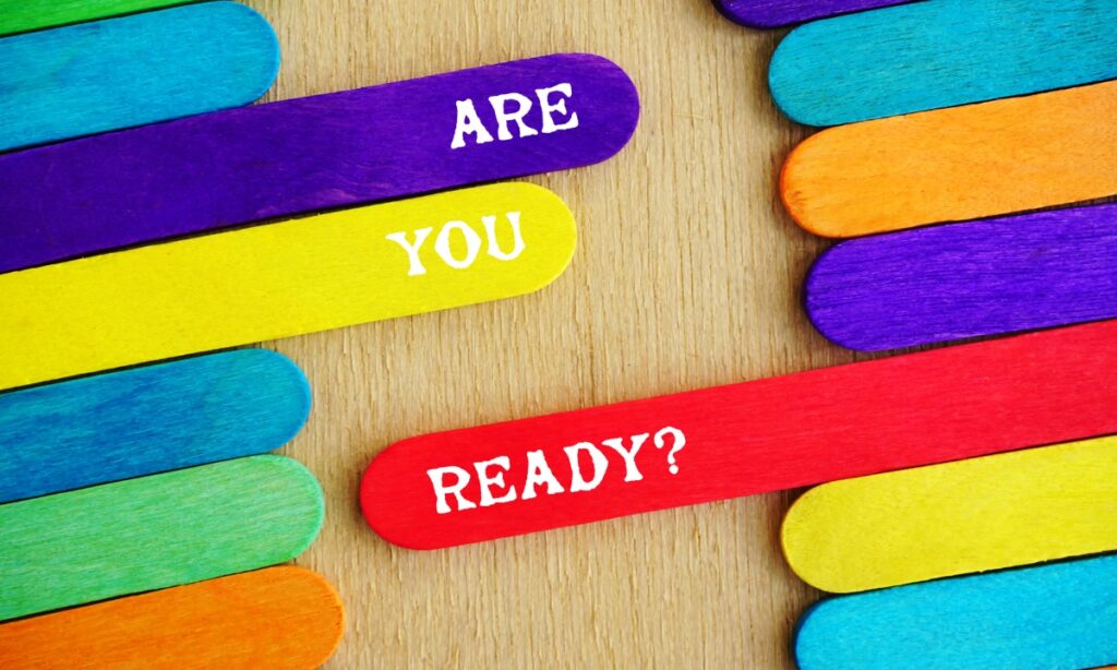 colored popsicle sticks lying on a wooden surface with three sticking out further than the others with the words "are you ready?" written on them