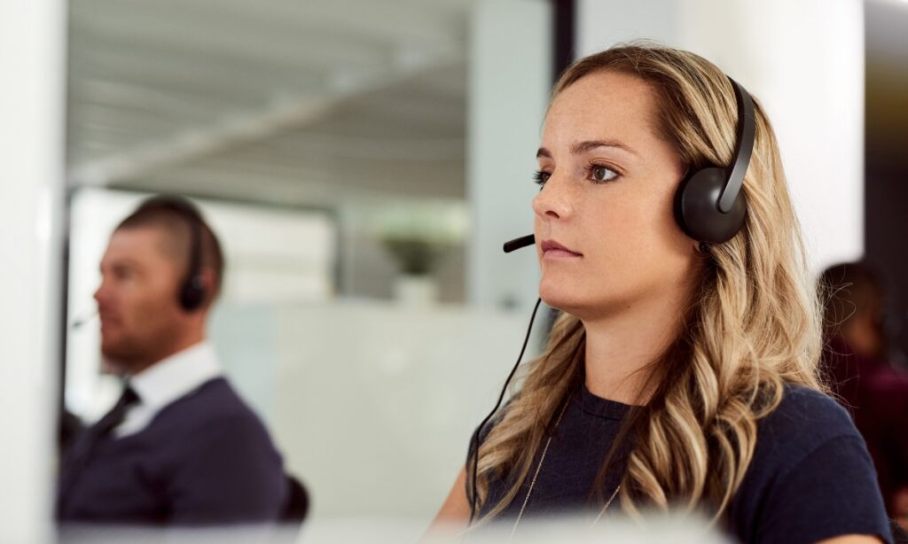 a woman looking at a computer while wearing a headset with a microphone