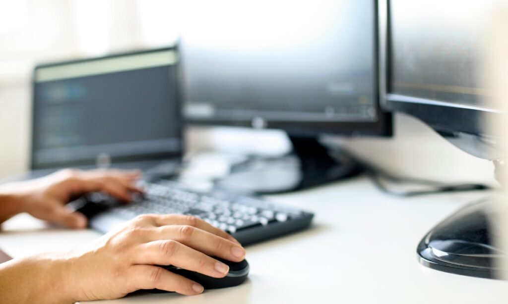 a person's hands on a computer keyboard and mouse