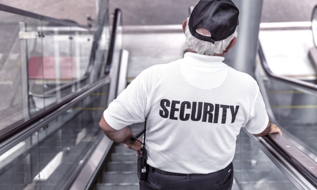 a security guard going down an escalator in a shirt that says "security"