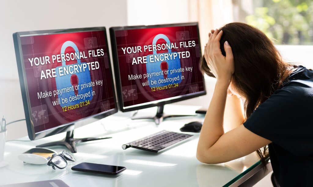 a woman with her head in her hands at the sigh of a ransomware notification on her computers